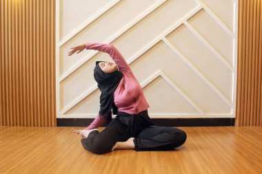Salonda yoga yapan Asyalı Müslüman kadın.