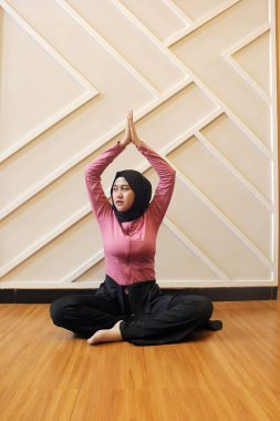 Yoga pozundaki Asyalı Müslüman kadın.