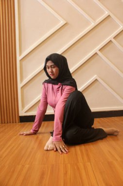 Genç Müslüman kadın evde yoga yapıyor.