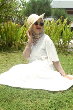 Beyaz tesettürlü, güneş gözlüklü Müslüman kadın.