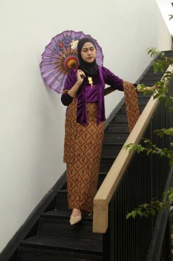 Geleneksel giyinmiş Asyalı Müslüman kadınlar ellerinde beyaz bir eşarp tutuyor.