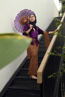 Atkı ve şemsiyeyle çatıda poz veren geleneksel elbiseli güzel bir kız.