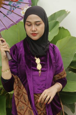 Mor geleneksel elbise ve fularlı Asyalı Müslüman kadın.
