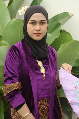 Eşarplı güzel Asyalı Müslüman kadın geleneksel bir Endonezya elbisesi giyiyor, fuları ve peçesi var..