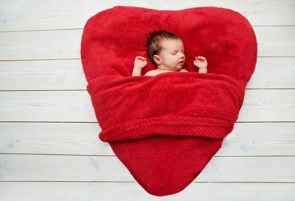 Bebê recém-nascido dormindo em um cobertor vermelho na forma de coração — Fotografia de Stock