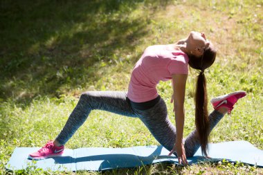 Genç kadın bir parkta germe