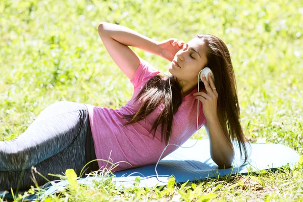 The girl in earphones has a rest ashore in summer day. Attractive young woman listening to music on the music player in the city outdoors. — Stock Photo, Image