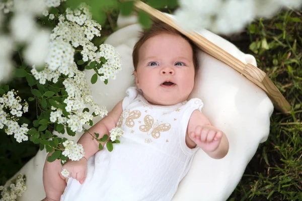 Horisontell bild av det leende nyfödda barnet utanför i blommande trädgård — Stockfoto