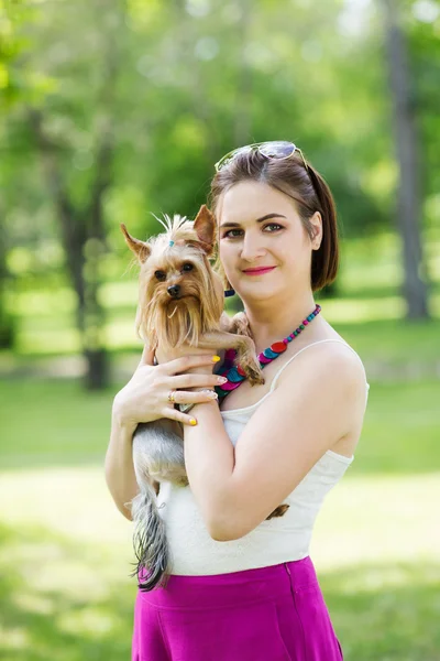 Hermosa joven feliz mujer sosteniendo perro pequeño en el día de verano paseos en el parque — Foto de Stock