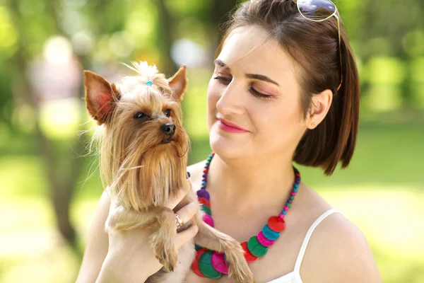 夏の日の小さな犬を保持している美しい若い幸せな女が公園で歩く — ストック写真