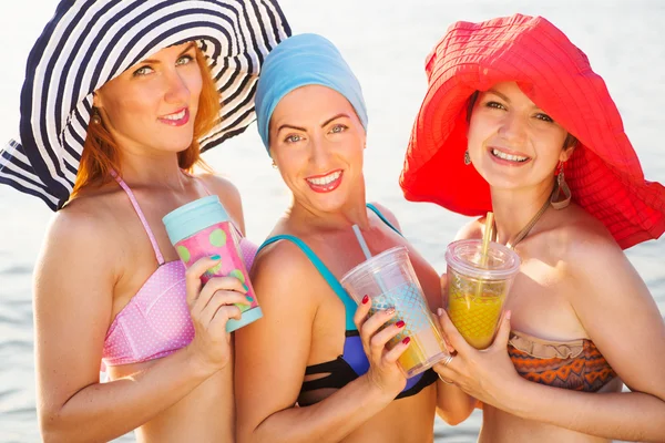 Holky pití koktejlů na pláži v bikinách — Stock fotografie