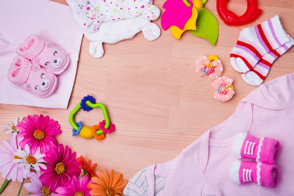 Novorozence baby oblečení s hračkami na dřevěné pozadí — Stock fotografie
