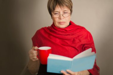 yaşlı kadın ile bir fincan çay ve kitap