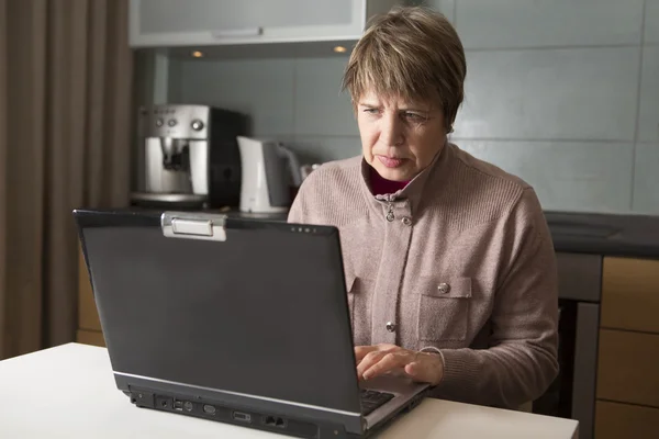 Пожилая женщина с ноутбуком в доме — стоковое фото