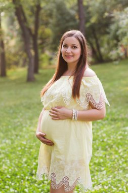 Genç mutlu hamile kadın doğada rahatlıyor ve eğleniyor.