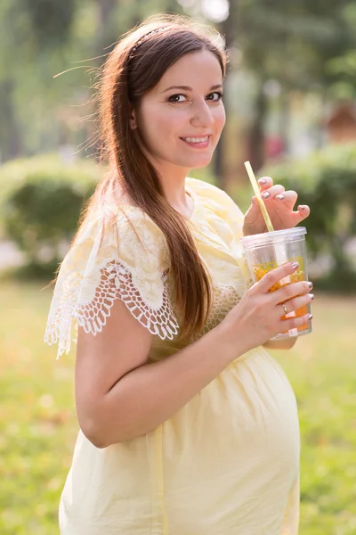 De mooie jonge zwangere vrouw met SAP dat in park in zomerdag — Stockfoto