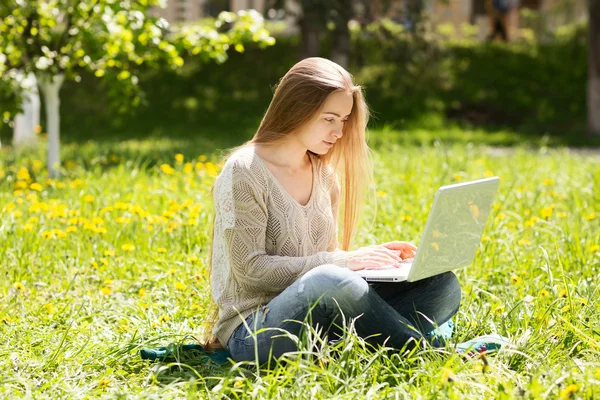 Молода жінка з ноутбуком на траві в парку — стокове фото