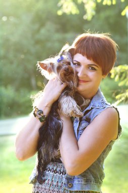 Küçük köpek yaz günü içinde tutan güzel genç mutlu kadın parkta yürüyor