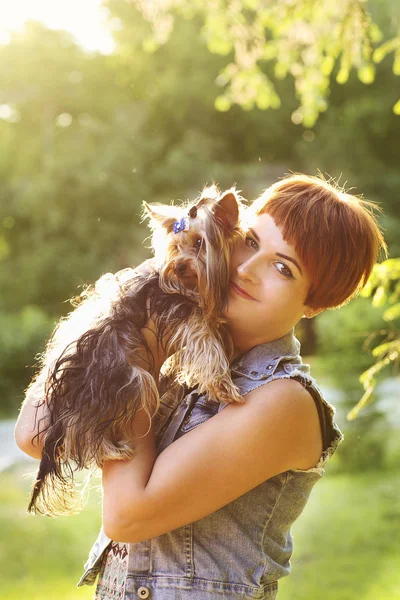 Belle jeune femme heureuse tenant un petit chien en été journée promenades dans le parc — Photo