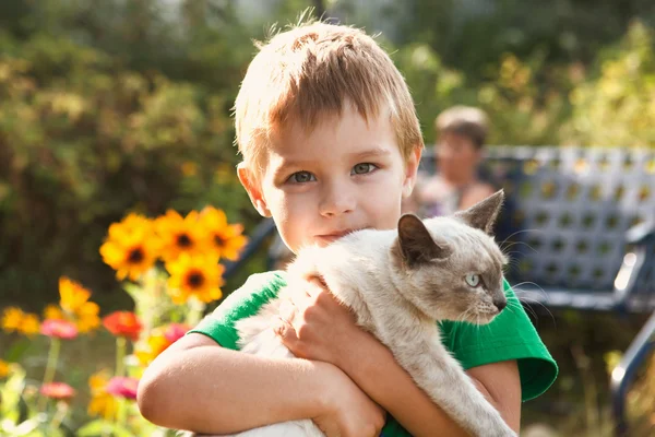 Le garçon tient en main un chat à l'extérieur — Photo