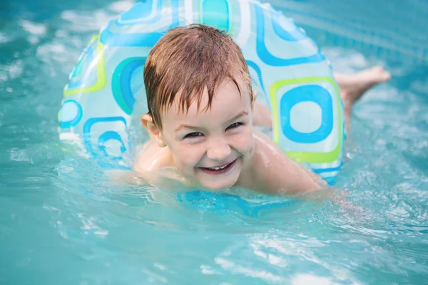 Menino nadando no anel de borracha da piscina, se divertindo em aquapark . Fotografia De Stock