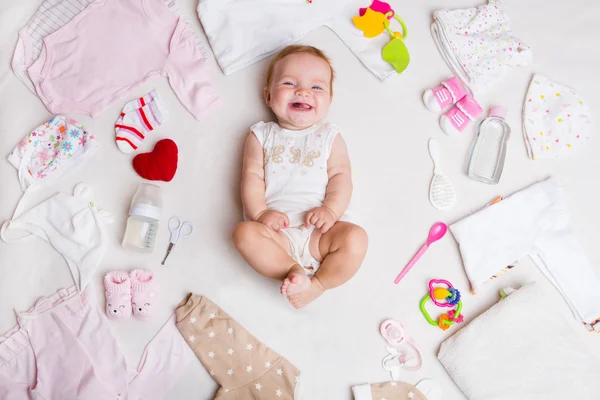 Baby na bílém pozadí s příslušenstvím, oblečení, toaletní potřeby, hračky a zdravotní péči. Seznam nebo nakupování přehled pro těhotenství a miminko. — Stock fotografie