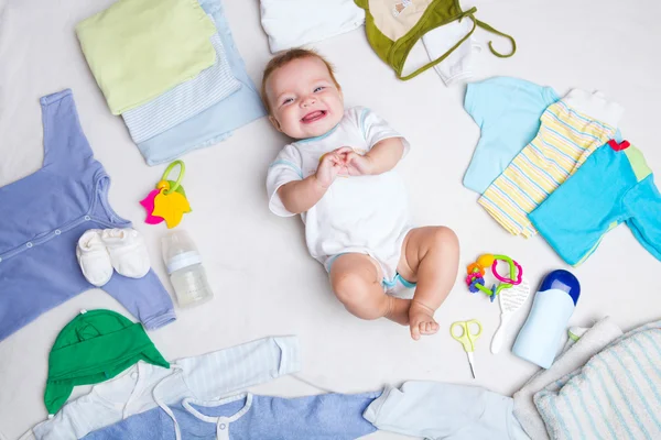 Bebé sobre fondo blanco con ropa, artículos de tocador, juguetes y accesorios para el cuidado de la salud. Lista de deseos o descripción general de compras para el embarazo y la ducha del bebé . —  Fotos de Stock