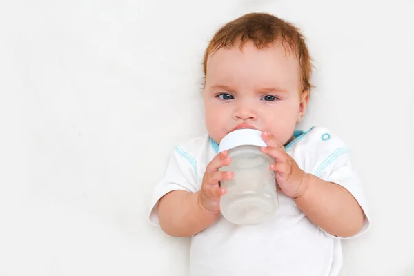 Baby holding bottle and drinking water Stock Picture