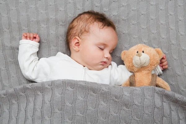 Bambino sdraiato sul letto.Bambino che dorme con il suo orsacchiotto, nuova famiglia e concetto di amore . — Foto Stock