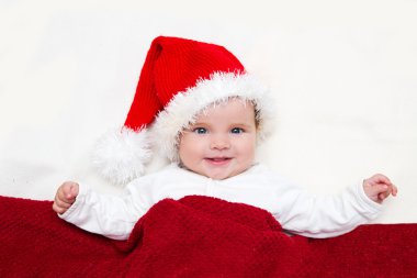 Gülümseyen genç bebek beyaz battaniye üzerinde Noel Baba şapkalı fotoğraflarını
