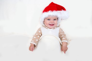Gülümseyen genç bebek beyaz battaniye üzerinde Noel Baba şapkalı fotoğraflarını