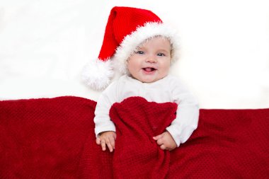 Gülümseyen genç bebek beyaz battaniye üzerinde Noel Baba şapkalı fotoğraflarını