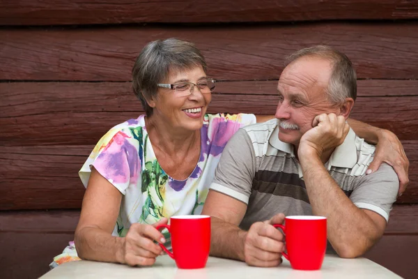 Прекрасная пожилая пара на открытом воздухе, пьющая из кружек — стоковое фото