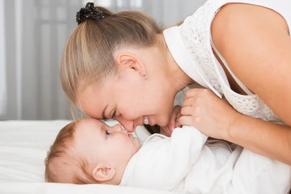 Familia feliz. madre jugando con su bebé en el dormitorio. — Foto de Stock