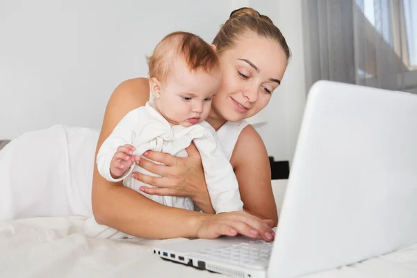 Lycklig mamma med hennes lilla flicka använder laptop hemma — Stockfoto