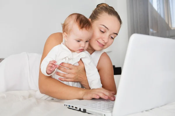 Mère heureuse avec son bébé fille en utilisant un ordinateur portable à la maison — Photo