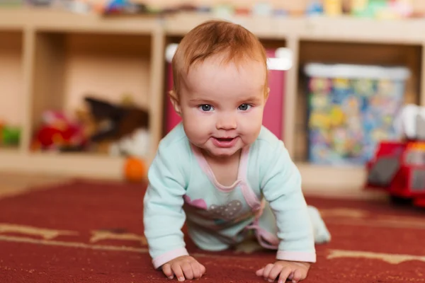 Bebê brincando e rastejando, fazendo rostos, no chão . — Fotografia de Stock