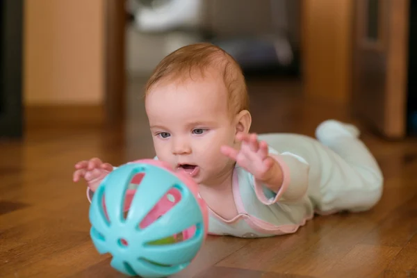 Baby spela och kryper, göra grimaser, på golvet. — Stockfoto