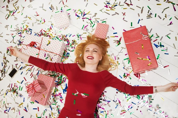 La mujer joven alegre con los regalos y los confeti en la habitación en el suelo — Foto de Stock