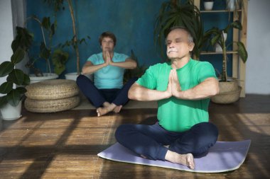 Yaşlı çift yoga yapıyor ve birlikte esniyorlar..