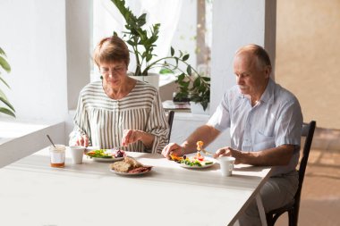 Yaşlı çift birlikte kahvaltı yapıyor..