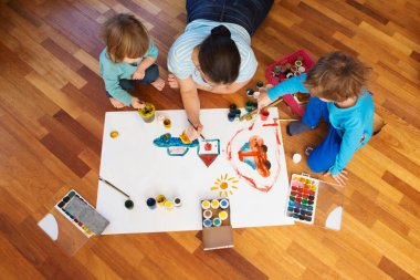 Çocuklar anneleriyle yerde resim çiziyor..