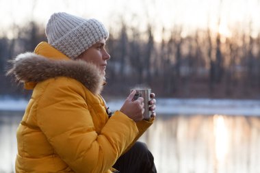 Sıcak çay içen ve baş döndürücü kış manzarasının yanında oturan bir kadın. Seyahat ve macera kavramı. Sıfır uçuş. Konaklamalar, hiper-yerel seyahat, kaçış.