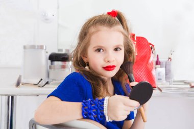 Mavi elbiseli şirin küçük kız makyajla oynuyor..