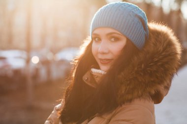 Güzel esmer kadın. Sıcak kışlık kıyafetler içinde. Sokakta poz veriyor.