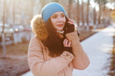 Güzel esmer kadın. Sıcak kışlık kıyafetler içinde. Sokakta poz veriyor.