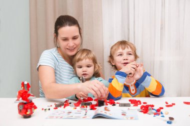 Anne ve kızı ve oğlu apartman dairesinde müteahhitle oynuyorlar. 