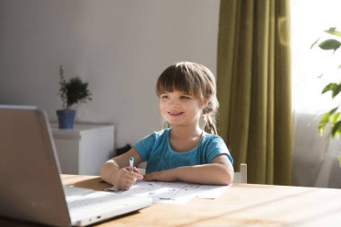 Çocuk bir dizüstü bilgisayar kullanıyor ve evdeki video öğretmeniyle internetten ders çalışıyor. Evde eğitim, uzak öğrenim