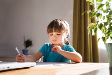 Çocuk bir dizüstü bilgisayar kullanıyor ve evdeki video öğretmeniyle internetten ders çalışıyor. Evde eğitim, uzak öğrenim