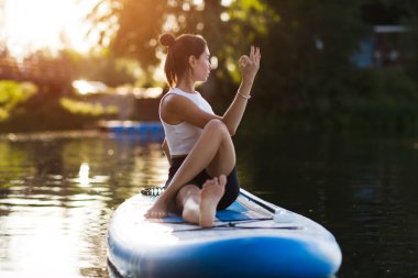 woman doing yoga on sup board at sunset. outdoor summer activity. Sup yoga. Social Distancing. copy space clipart